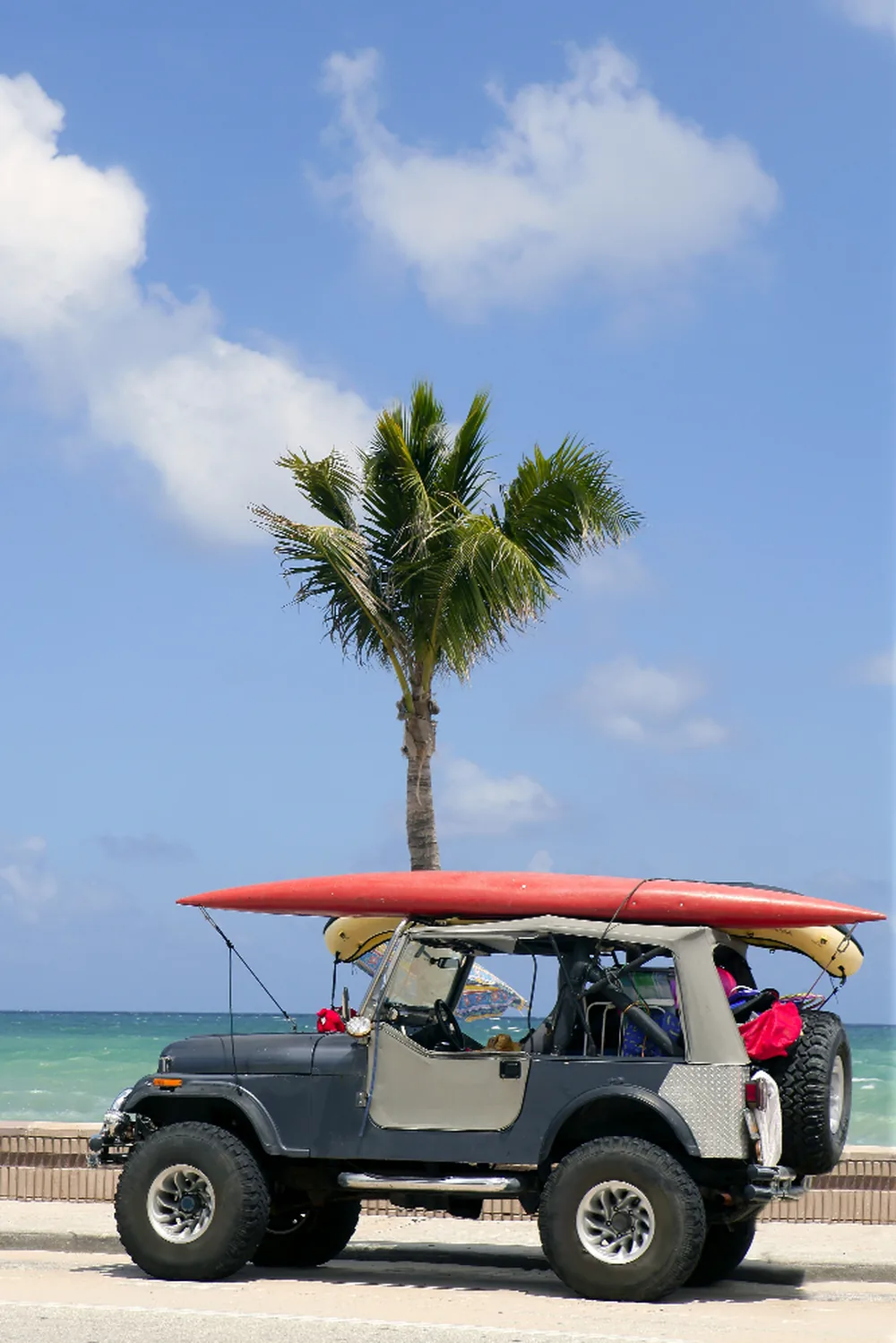Offener Jeep mit Surfbrettern an einem Strand einer Bahamas-Out-Island